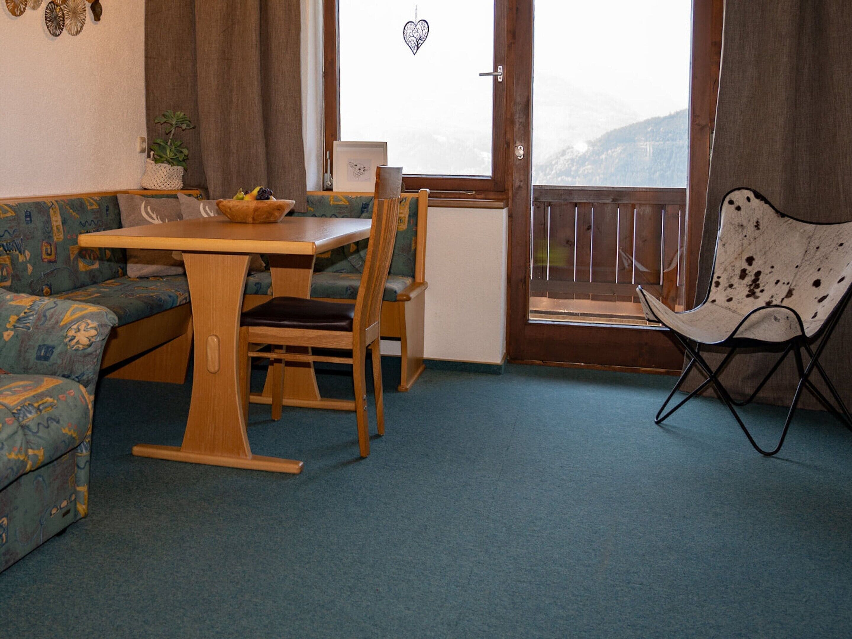 A cozy room with a wooden table, a blue patterned sofa, and a metal folding chair.