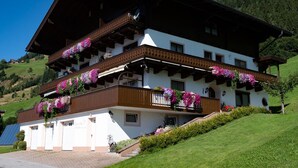 Un chalet alpino tradicional con techo inclinado, balcones de madera y jardineras con flores.