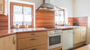 Een moderne keuken met houten kastjes, een roestvrijstalen afzuigkap en een inbouwoven.