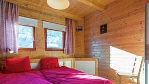 Een houten kamer met twee bedden, een bureau en een stoel.