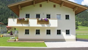 A two-story building with a sloped roof, multiple windows, and wooden balconies with flower boxes. - Apartment in Aschau Near Hochzillertal Slopes (Aschau Im Zillertal)