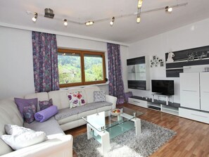 A modern living room with a sofa, coffee table, TV, and cabinets. - Apartment in Stumm Near Ski Slopes (Stumm)