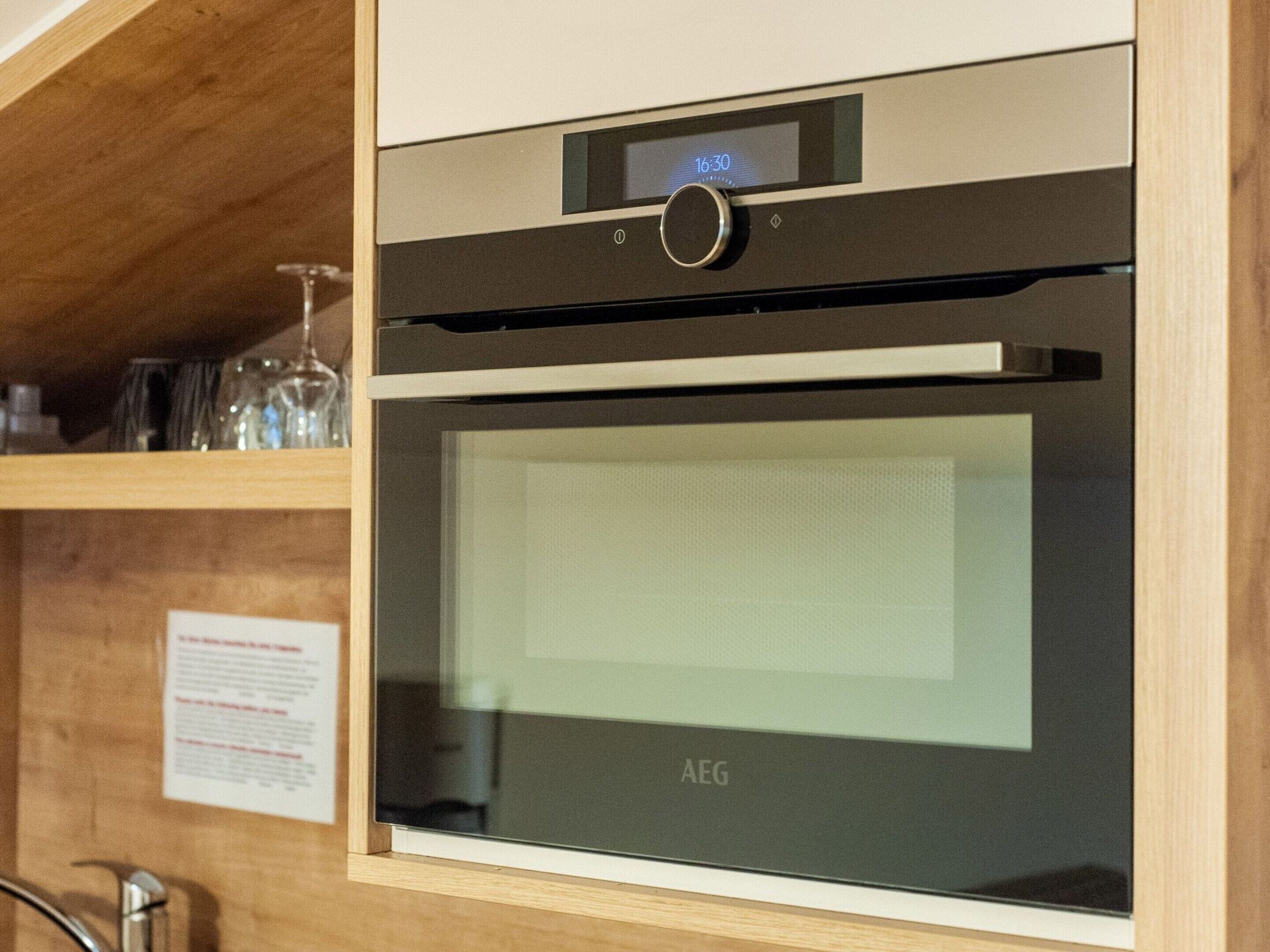 A modern kitchen with a built-in oven and a digital clock displaying 16:30.