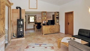 A spacious living area with a fireplace, wooden furniture, a sofa, and a television.