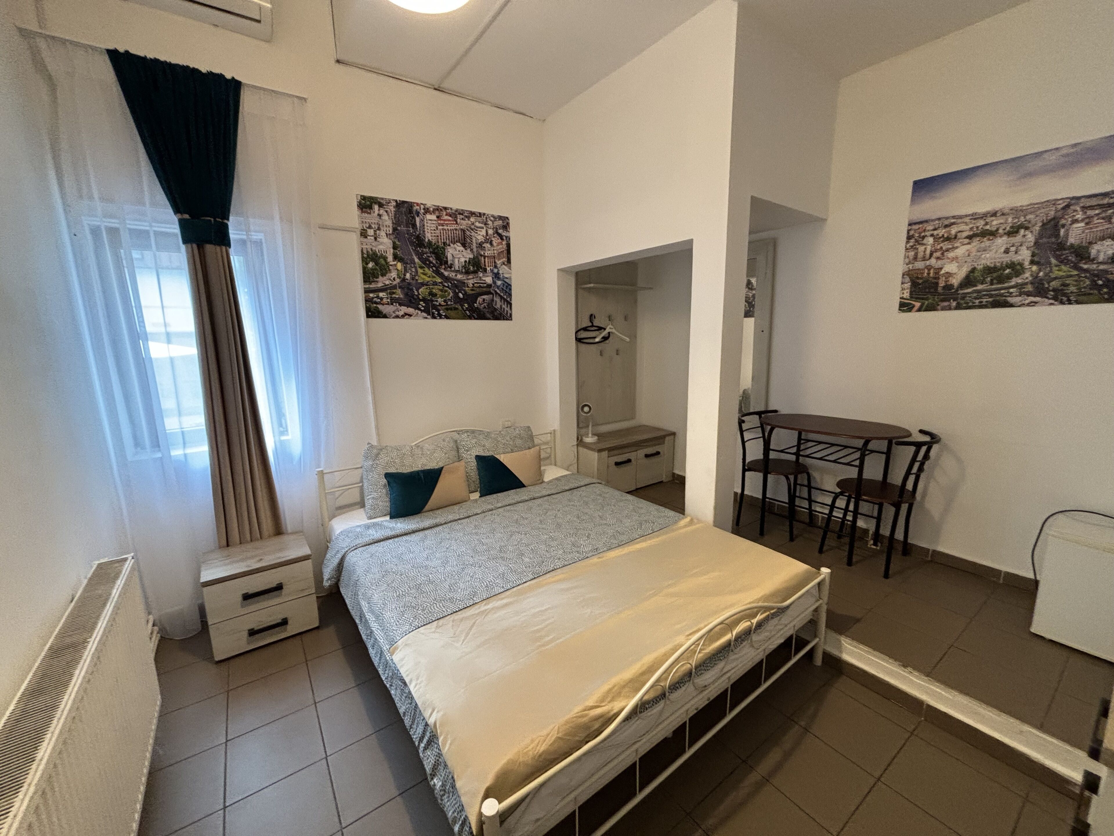 Un dormitorio con cama, mesitas de noche, un escritorio y sillas.