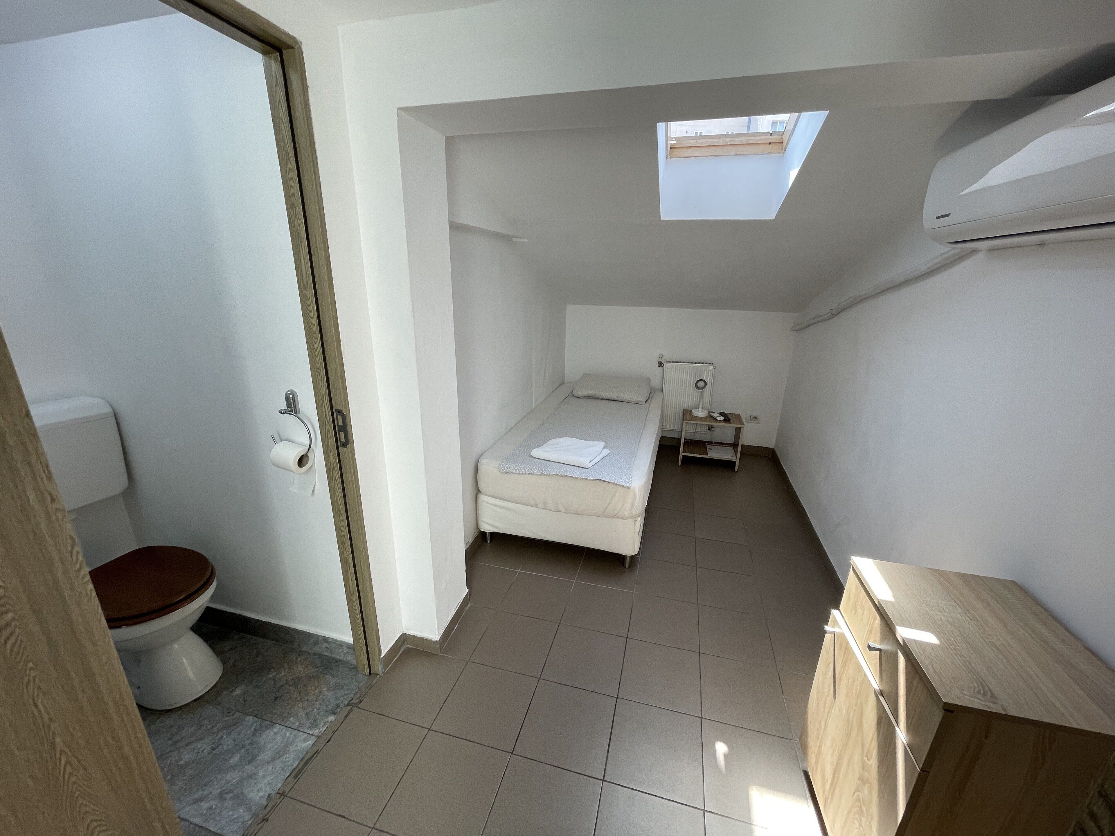 Ein gemütliches Schlafzimmer mit Dachfenster, einem Einzelbett, einem Nachttisch und einem kleinen Beistelltisch.