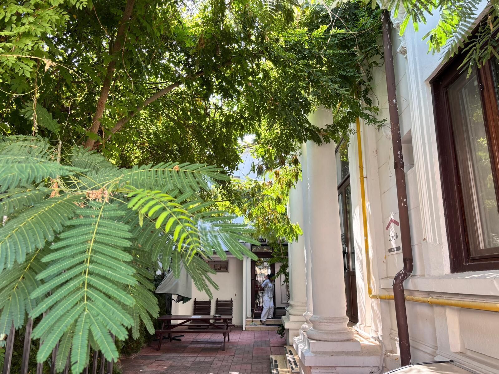 Un patio con un banco, una mesa y una persona caminando.
