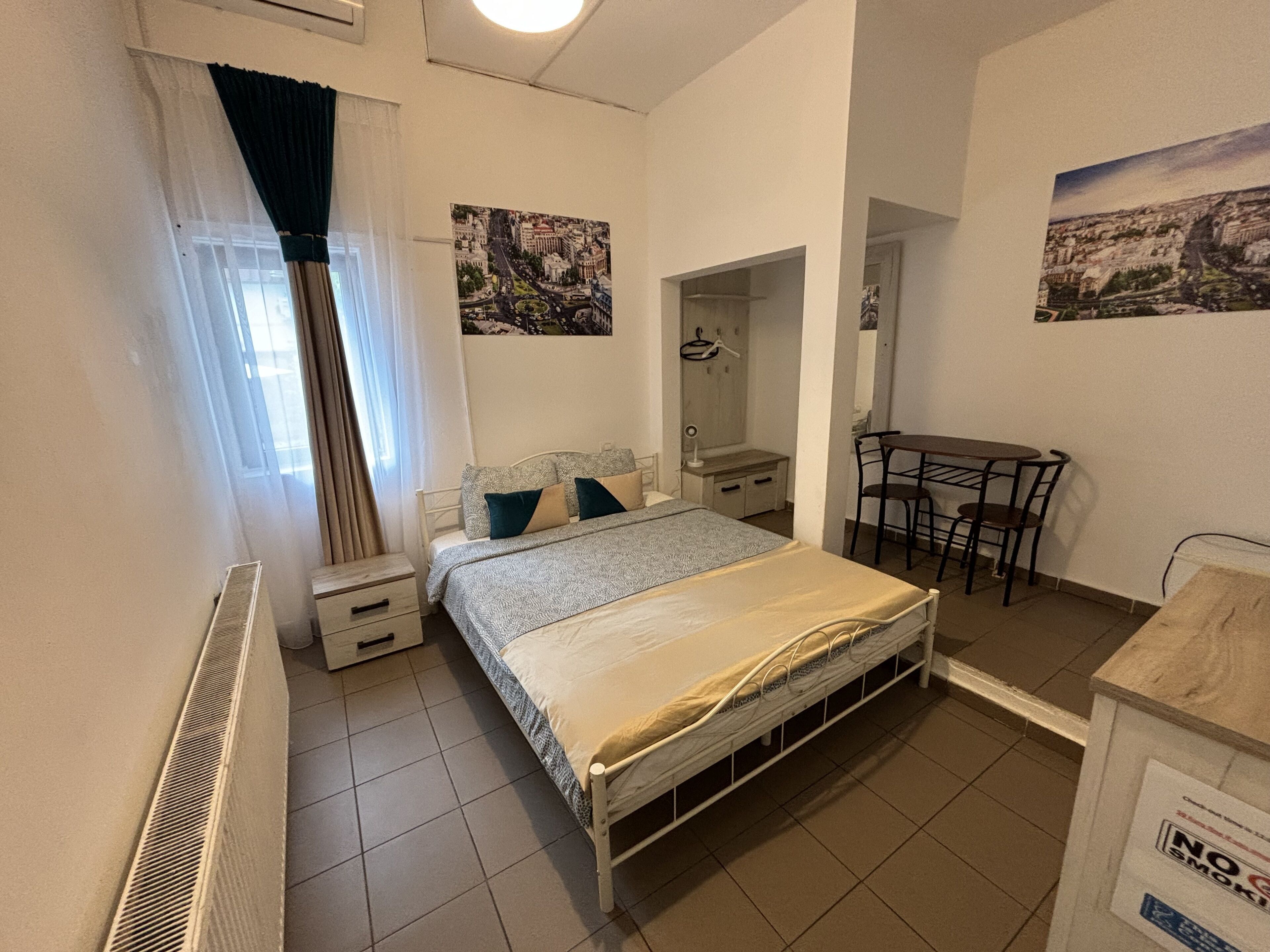 A bedroom with a bed, a desk, a chair, a radiator, and a mirror.