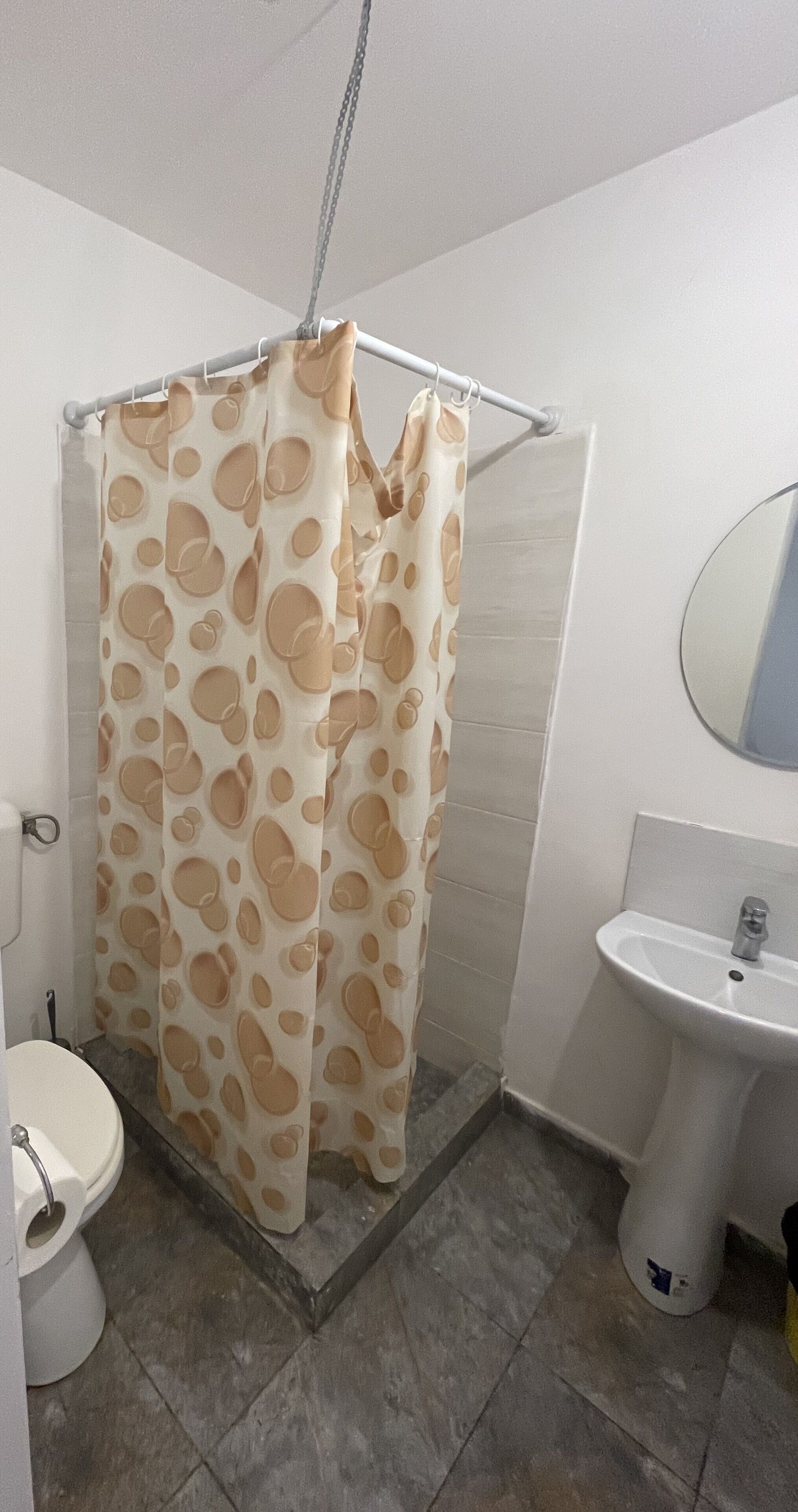 Ein Badezimmer mit Duschvorhang mit Punkten, einem weißen Waschbecken und einer Toilette.