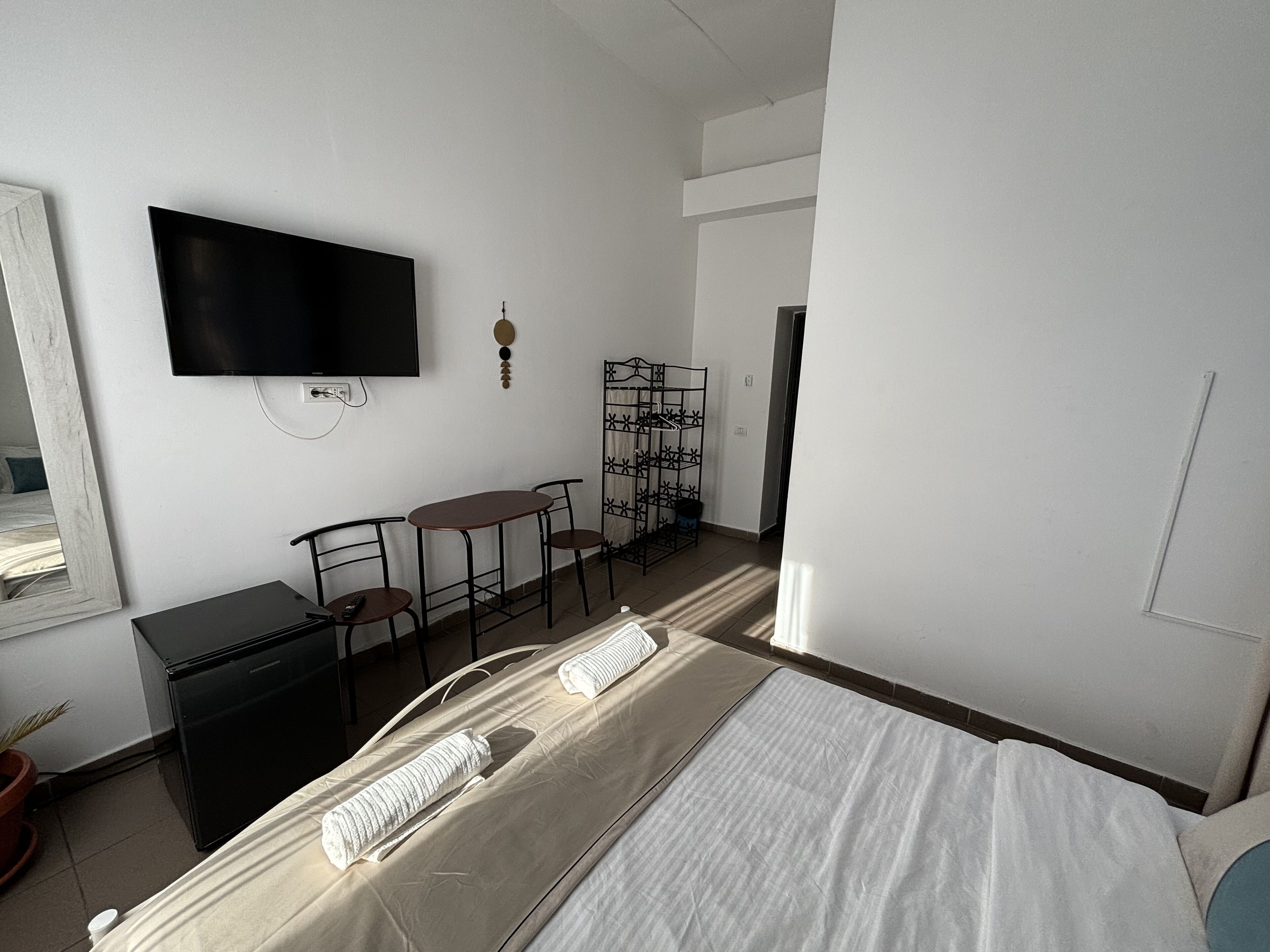 Una habitación de hotel con cama, escritorio, silla, televisor y una mesita.