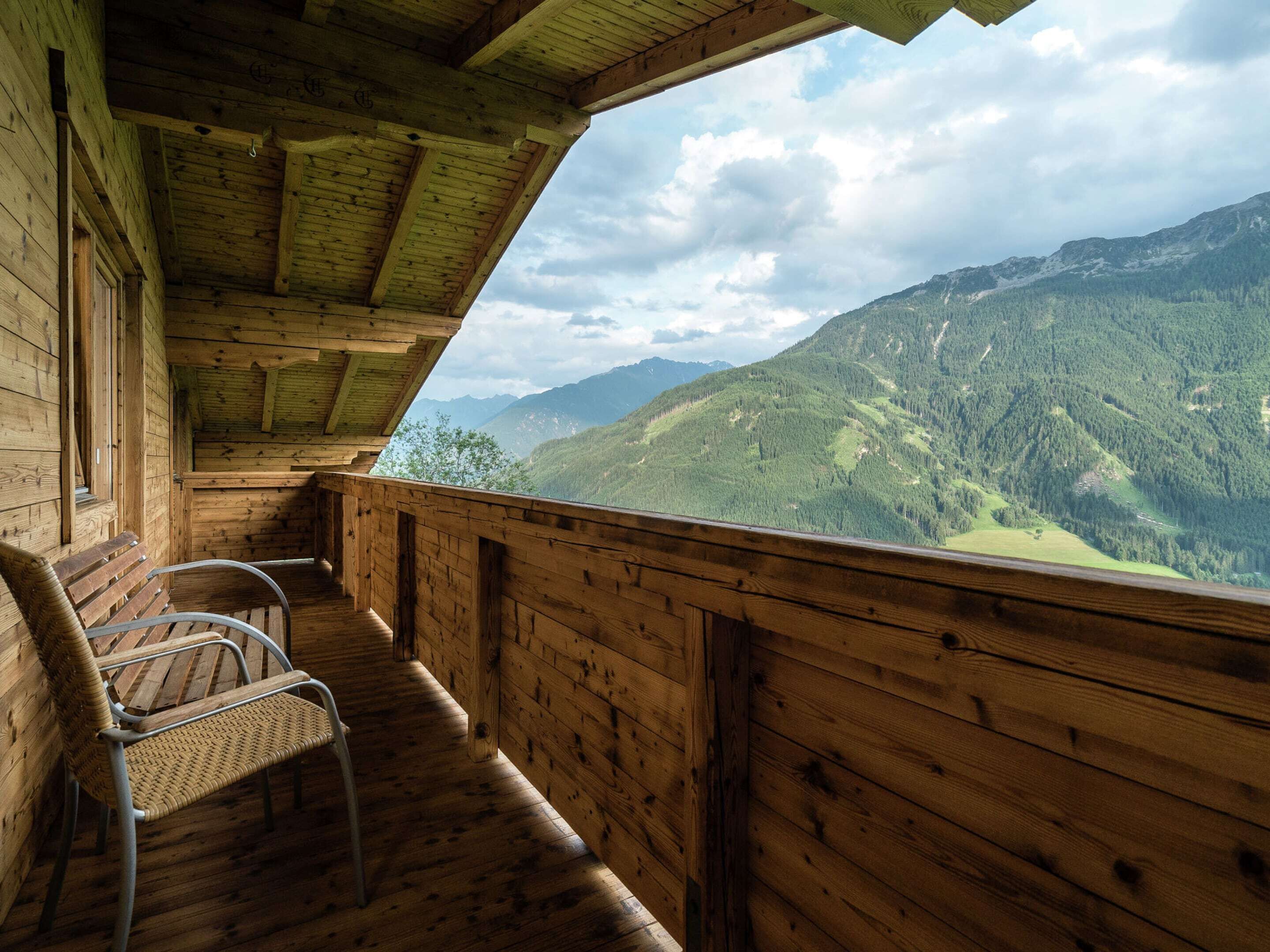 A wooden cabin with a balcony overlooking a mountainous landscape.