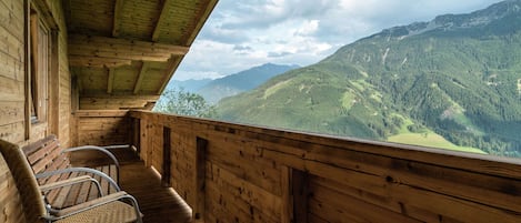 Una cabaña de madera con balcón que da a un paisaje montañoso.