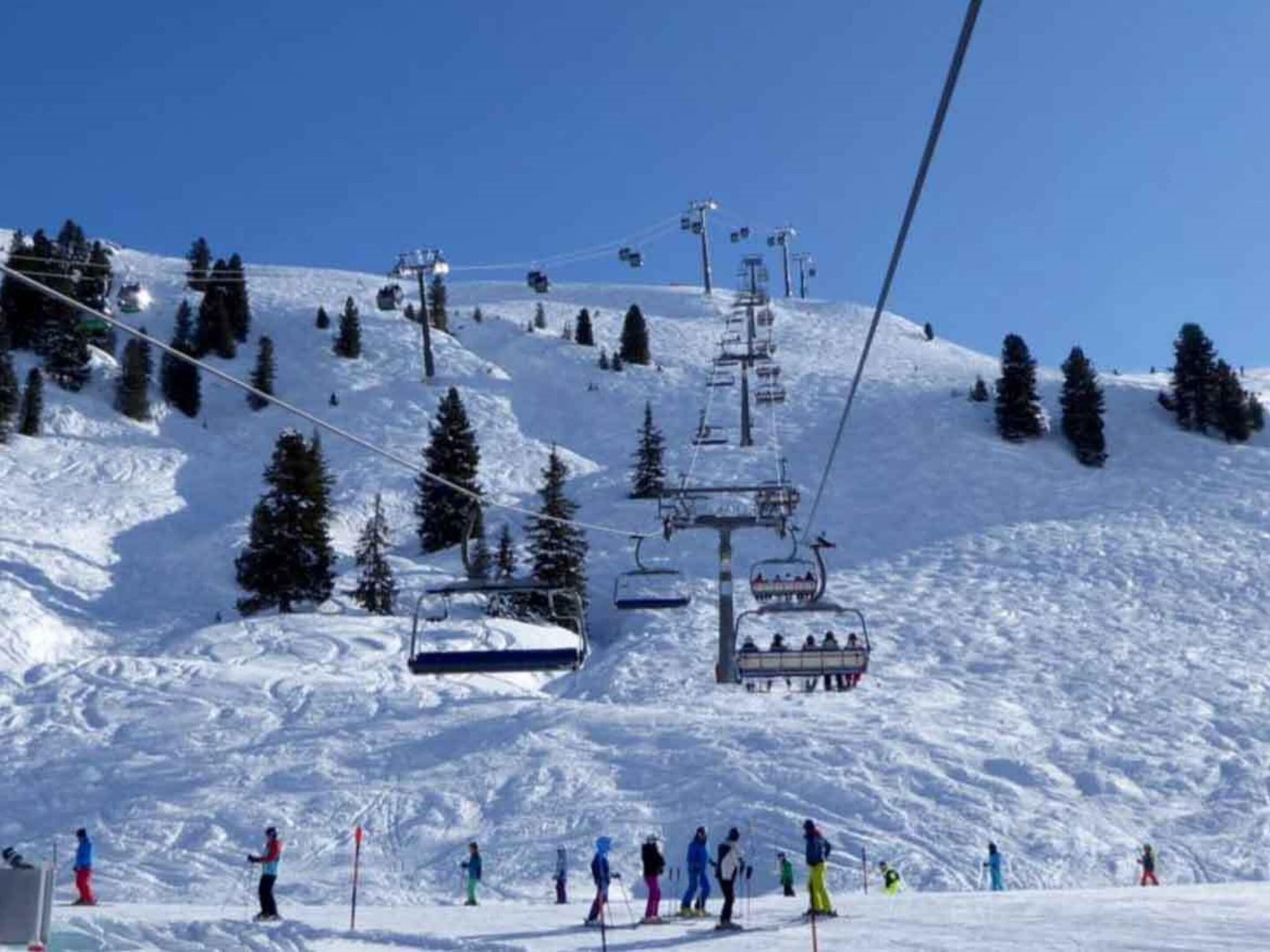 A ski lift with skiers on a snowy slope.