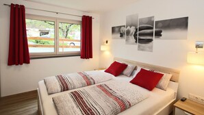 Habitación de hotel con cama, cortinas rojas, ventana que da a la vista exterior y decoración en las paredes.