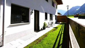 Un edificio moderno con amplios ventanales, un pequeño espacio al aire libre y vistas a las montañas.
