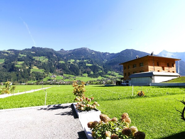 A house with a sloped roof, surrounded by a well-maintained lawn and a gravel path.