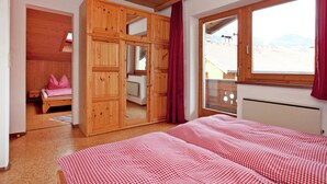 Ein Schlafzimmer mit einem großen Bett, einem Holzschrank und einem Fenster mit Blick.
