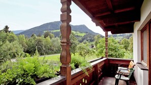 Ein Holzbalkon mit Blick auf eine grüne Landschaft und Berge.