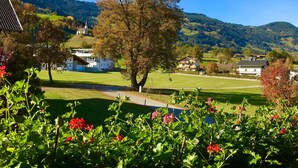 Ländliche Landschaft mit Häusern, einer Kirche und Bergen im Hintergrund.