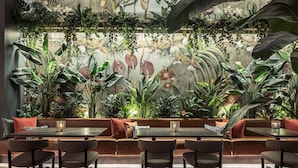 Un restaurant doté d’un long banc servant de siège, de tables et d’une variété de plantes.