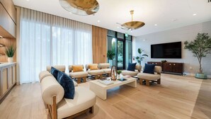 Un salon spacieux comprenant un ensemble de canapés, une table basse et un téléviseur à écran plat fixé au mur.