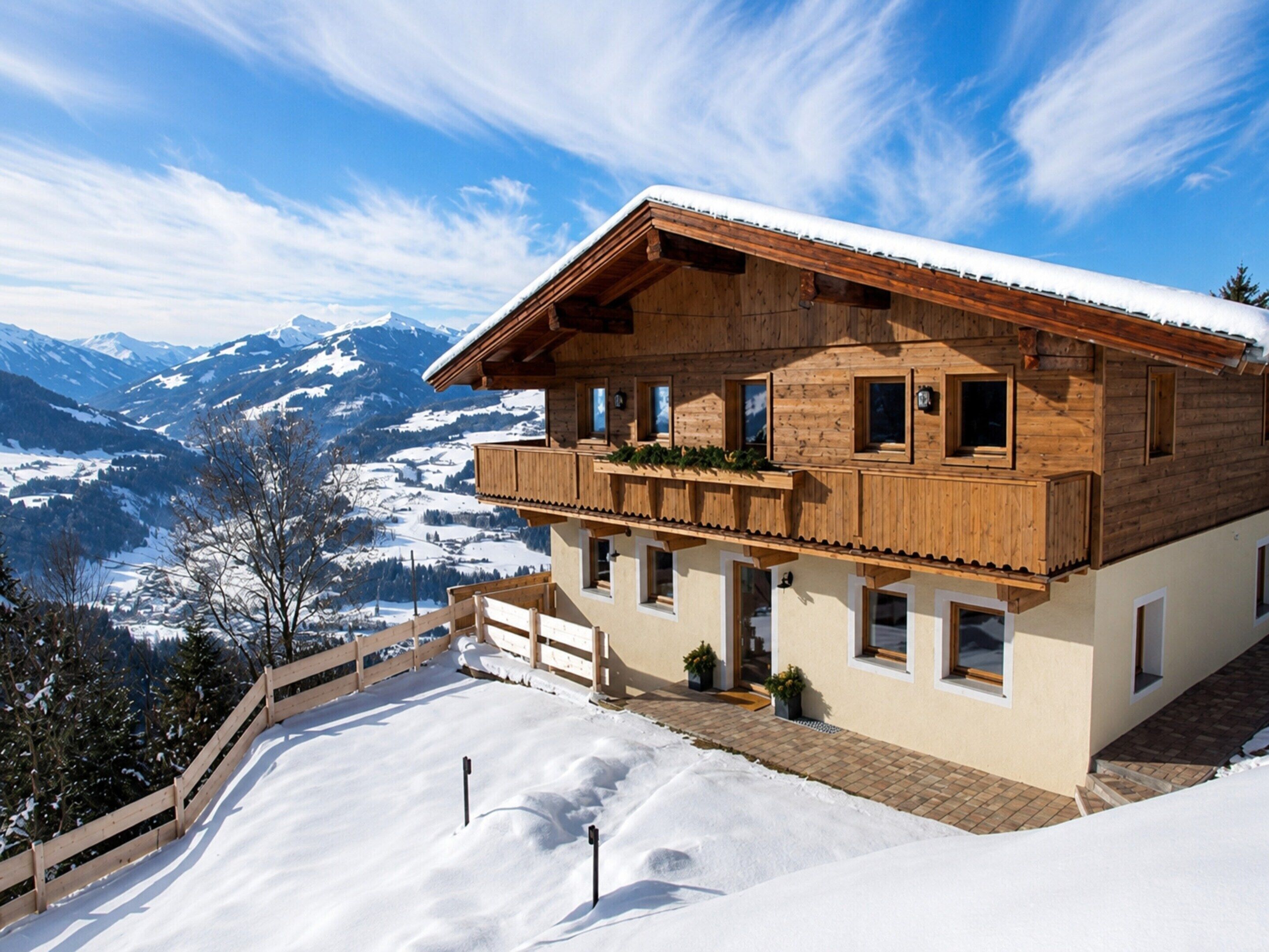 A wooden chalet with a balcony overlooking a snowy mountain landscape.