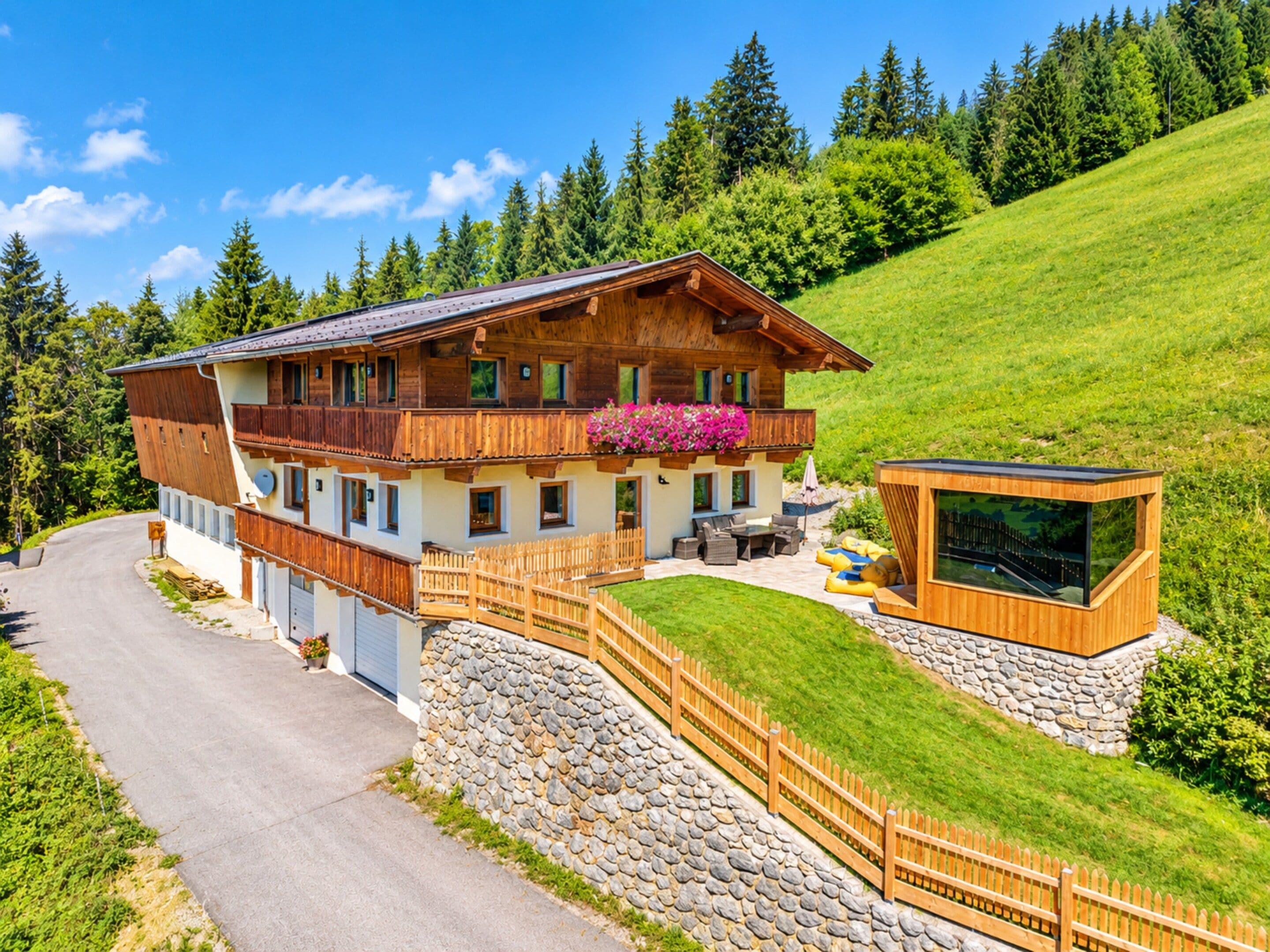 Ein Chalet mit Balkon, Steinmauer und Holzterrasse.