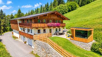 Ein Chalet mit Balkon, Steinmauer und Holzterrasse.