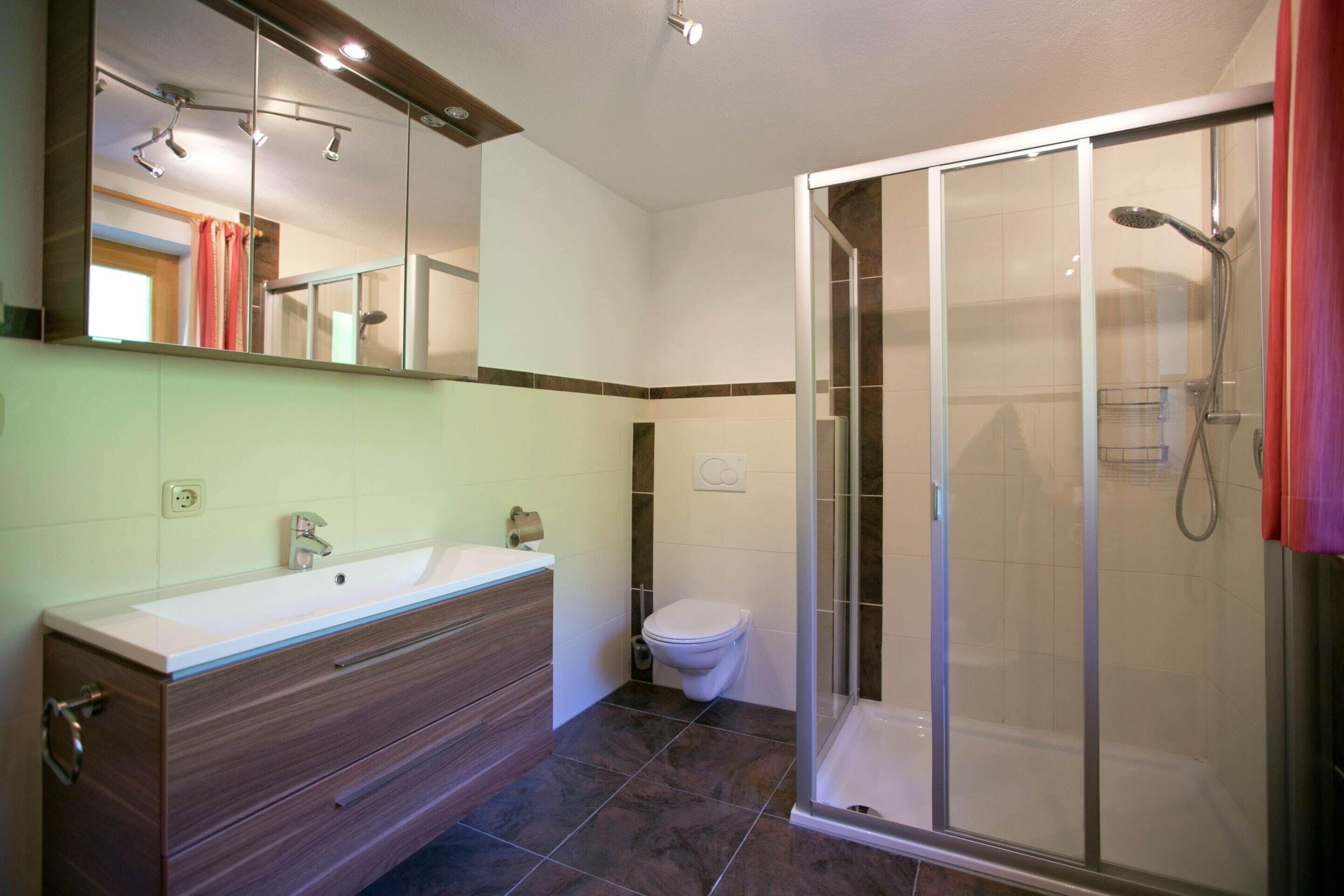 Un baño con ducha, inodoro y tocador.