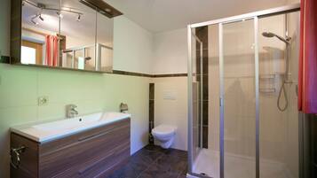 Un baño con ducha, inodoro y tocador.