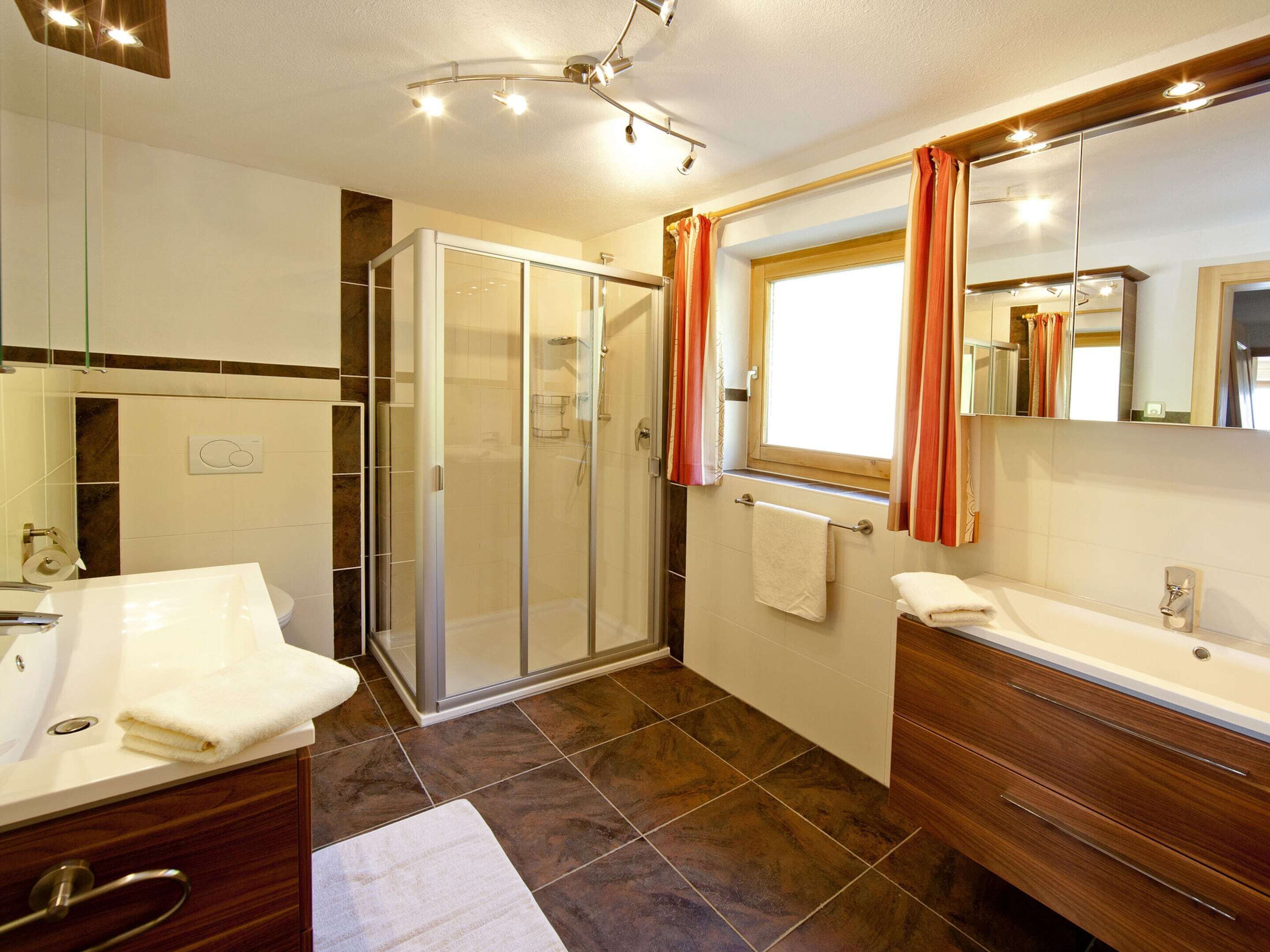 A modern bathroom with a glass shower enclosure, a vanity with a mirror, and a bathtub.
