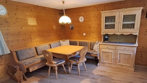 En inredning med träpanel, ett matbord, bänkar, en köksdel och en klocka på väggen.