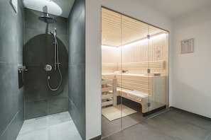 A modern bathroom with a glass-enclosed shower, a wooden sauna, and a visible sauna bench. - Chalet in Piesendorf Near Ski Slopes (Piesendorf)