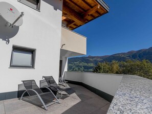 A modern building with a balcony, a satellite dish, and a view of mountains.