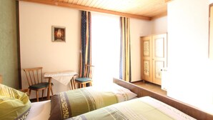 A room with two beds, a wooden ceiling, a table with chairs, and a door with decorative glass panels. - Lovely Apartment in Mittersill near Kitzbühel - Kirchberg (Mittersill)