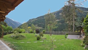 A well-maintained garden with a wooden pergola, a small tree, and a stone pathway leading to a wooden deck. - Apartment at the City Center in Brandberg (Brandberg)