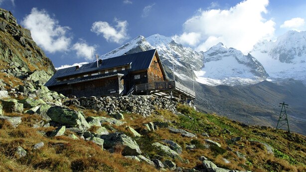 A mountain lodge with a wooden exterior, stone foundation, and a view of snow-capped peaks. - Apartment at the City Center in Brandberg (Brandberg)