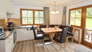 A modern kitchen with a dining area, wooden cabinets, a coffee maker, and large windows. - Apartment at the City Center in Brandberg (Brandberg)