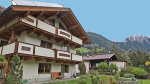 A multi-story chalet with a sloped roof, wooden balconies, and a garden with a stone wall and greenery. - Apartment at the City Center in Brandberg (Brandberg)