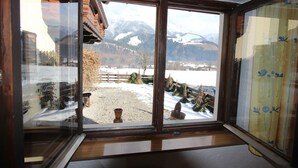 Een kamer met een groot raam dat uitzicht biedt op een besneeuwd landschap en bergen.