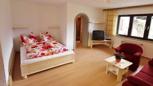 Een slaapkamer met een bed, televisie en een rode stoel.
