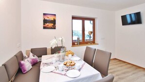 A dining area with a table set for four, a window with a view, and a flat-screen TV on the wall. - Chalet in Wald Near Zillertal Ski Area (Wald im Pinzgau)