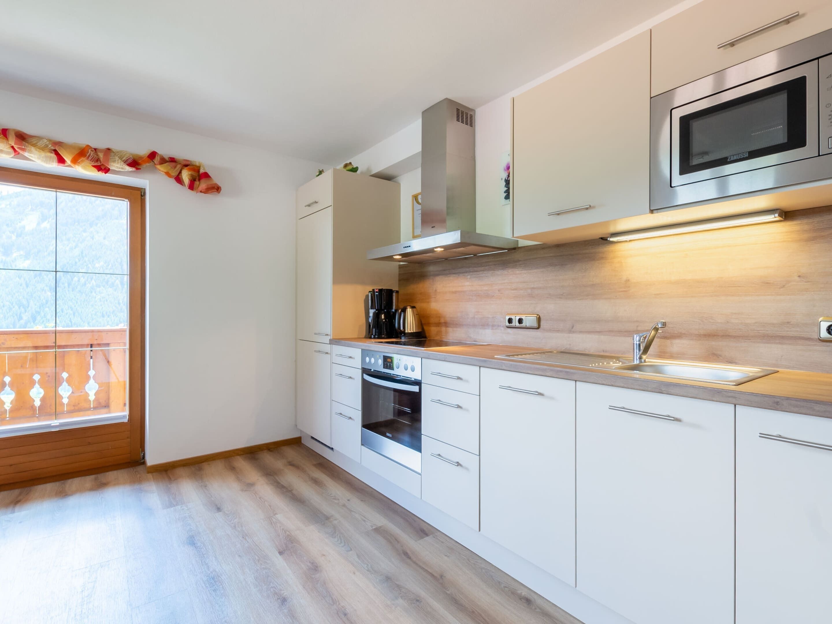 Een moderne keuken met witte kasten, een roestvrijstalen magnetron en een inbouwoven.