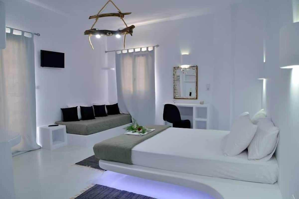 Une chambre à coucher moderne et minimaliste, avec un grand lit, un petit bureau, une chaise et un téléviseur.