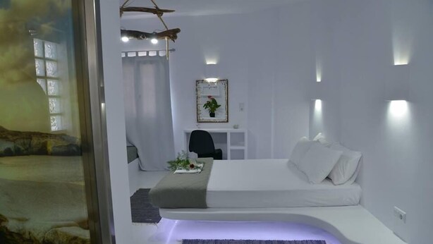 A modern bedroom with a curved bed, a desk, and a chair. - Moschoula studios (Milos)
