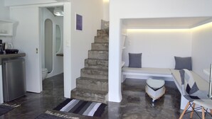 A modern interior with a staircase, a seating area with cushions, and a small table. - Moschoula studios (Milos)