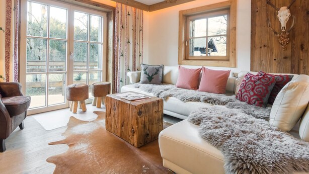 A cozy living room with a large window, wooden beams, a white sofa, and a coffee table. - Chalet in Ellmau Near Ski Slopes (Ellmau)