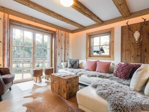 Una sala de estar acogedora con un ventanal grande, vigas de madera, un sofá blanco y una mesa de centro.