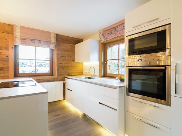 Una cocina moderna con detalles de madera, horno empotrado y ventana con vistas.