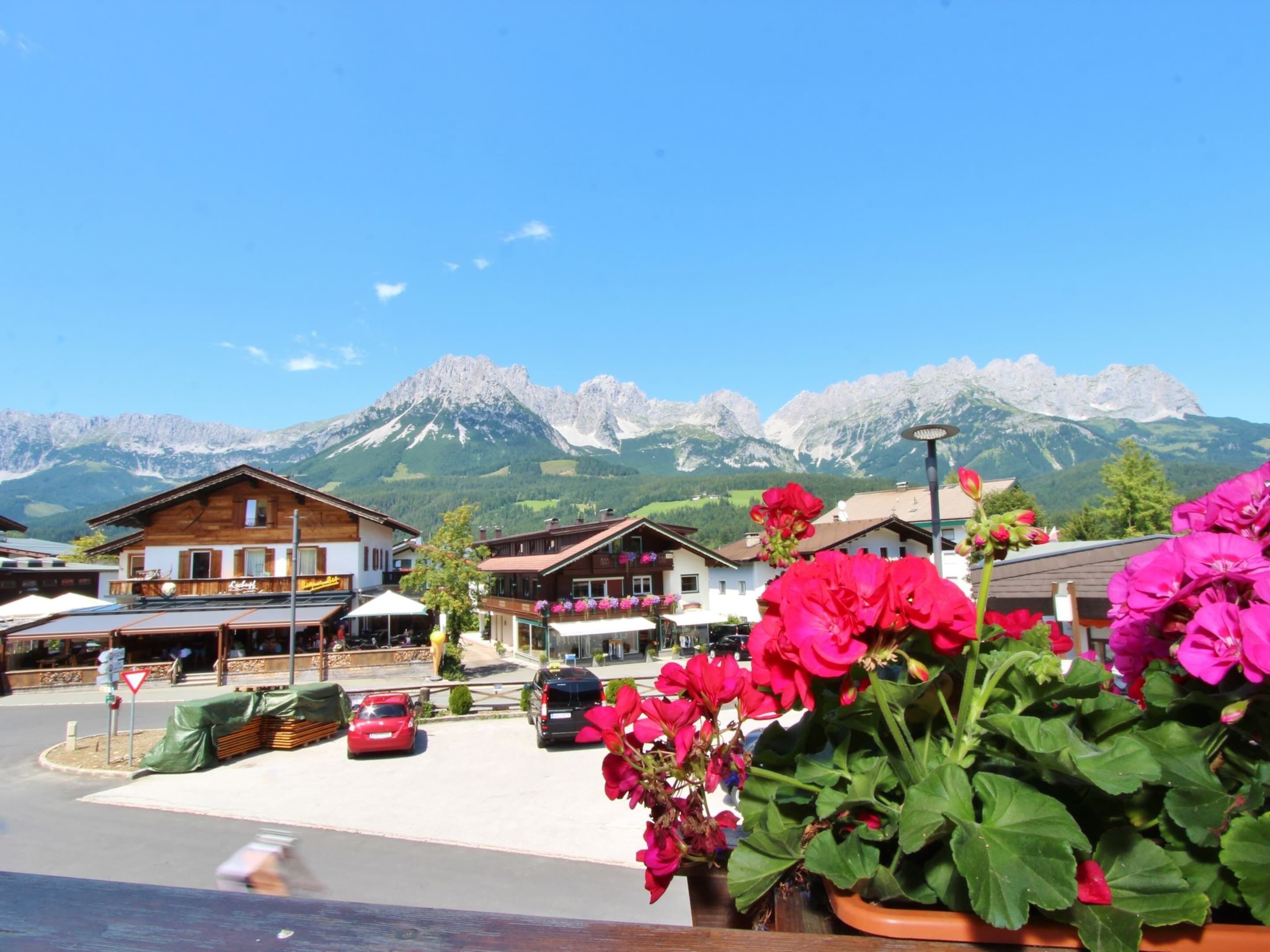 A mountain town with wooden buildings, a street with parked cars, and a view of snow-capped mountains.